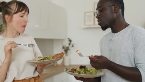 Young-Diverse-Couple-Eating-Salad-and-Speaking
